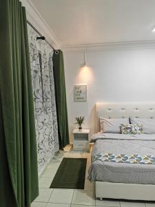 sypialnia z łóżkiem i zielonymi zasłonami w obiekcie Sunrise Bedrooms and Transit w mieście Ranau
