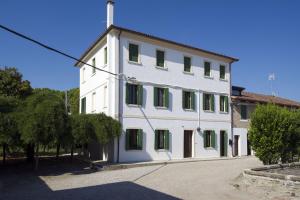 a large white building with green shuttered windows at Casa Sincielli in Caorle