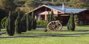 a house with a wagon wheel in front of a garden at Orillas del Coilaco in Pucón