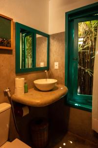 ein Badezimmer mit einem Waschbecken, einem Spiegel und einem WC in der Unterkunft Pousada Nativa in Caraíva