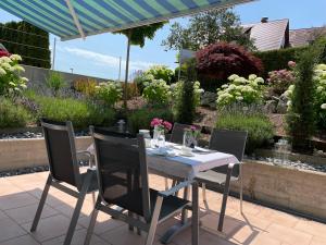 einen Tisch und Stühle auf einer Terrasse mit Garten in der Unterkunft SEEZEIT Residence in Hagnau