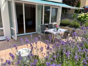 eine Terrasse mit einem Tisch und lila Blumen in der Unterkunft SEEZEIT Residence in Hagnau