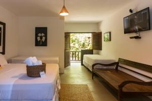 Zimmer mit 2 Betten, einem TV und einer Bank in der Unterkunft Pousada Nativa in Caraíva
