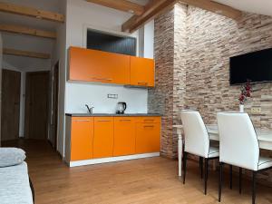 een keuken met oranje kasten en een tafel met witte stoelen bij Apartmán U Póla in Zdíkov