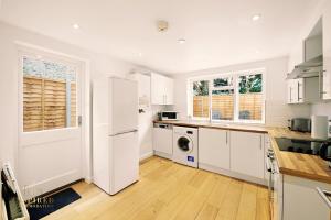 a kitchen with white cabinets and a white refrigerator at Broomsleigh NW6 Apartment in London