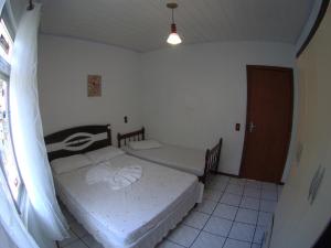 two beds in a small room with a window at Olhar da Barra Hospedagem - Casa Branca in Florianópolis