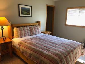 a bedroom with a bed and a lamp and a window at River Run Inn in Winthrop