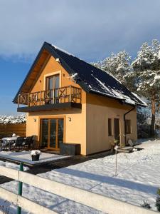 a small house with a balcony in the snow at Zakątek Ciszy. in Słuchowo