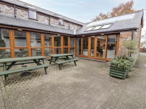 a patio with two picnic tables in front of a building at Ddol Helyg Barn in Cwm-y-glo
