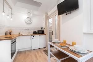 a kitchen with white cabinets and a table with food on it at Modern Self Contained Studio Home in Cheltenham