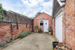 an alley between two brick buildings with a white door at Modern Self Contained Studio Home in Cheltenham