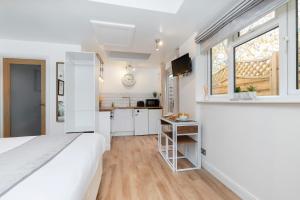 a white bedroom with a large bed and a kitchen at Modern Self Contained Studio Home in Cheltenham