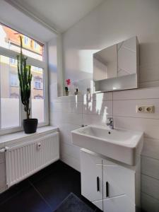 een witte badkamer met een wastafel en een raam bij Neu sanierte Wohnung mit Balkon und Stellplatz in Erfurt