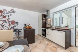 kuchnia z białymi szafkami i stołem w obiekcie Apartment Dignano w mieście Vodnjan