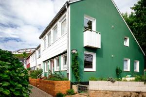 a green and white house with a balcony at Greenhouse Apartments in Helgoland