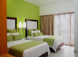 two beds in a hotel room with green walls at Cancun Bay Resort - All Inclusive in Cancún