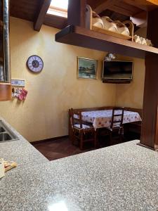 eine Küche mit einem Tisch und einer Uhr an der Wand in der Unterkunft Espoire - grande rochere in La Salle