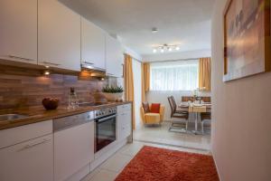 a kitchen with white cabinets and a dining room at Apart Blassnig in Maurach