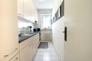 a small kitchen with white cabinets and a refrigerator at Charming Minusio Apartment, close to Locarno&Lake in Minusio