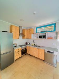 eine Küche mit Holzschränken und einem Kühlschrank aus Edelstahl in der Unterkunft Kali Vice Surf Villa in Costa da Caparica