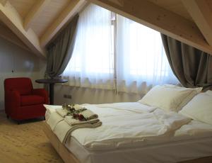 ein Schlafzimmer mit einem Bett und einem roten Stuhl in der Unterkunft Agriturismo Casa Preti in Revò