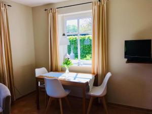 a dining room table with white chairs and a window at Am Eichberg in Wieck