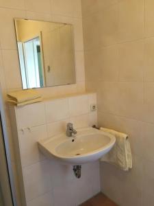a white bathroom with a sink and a mirror at Am Eichberg in Wieck +9 photos