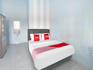 a bedroom with a bed with red pillows on it at OYO Life 91399 Homestay Trendy Syariah in Cilacap