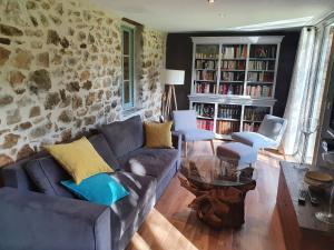 sala de estar con sofá y pared de piedra en Gite de la Genevrière en Saint-Chamant