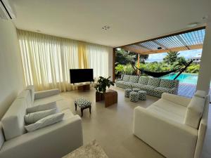 a living room with white couches and a television at Casa em Praia do Forte - Bahia in Praia do Forte