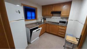 kuchnia z białą lodówką i drewnianymi szafkami w obiekcie Precioso apartamento con piscina cerca de la playa w mieście Benidorm