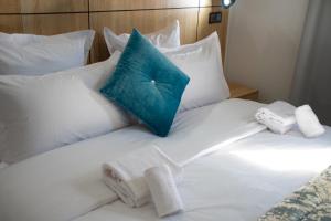 Una cama blanca con toallas y una almohada azul. en Karam City Hotel, en Dakhla
