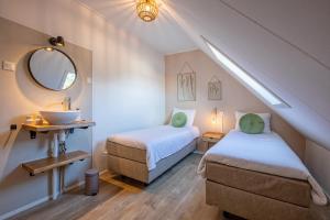 2 camas en una habitación con lavabo y espejo en De Leeuwerik en De Koog