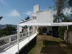 Casa blanca con porche blanco con sombrilla blanca en AHEV en Villa Carlos Paz