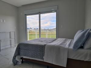 a bedroom with a bed and a large window at Recanto Brisa e Mar in Palhoça