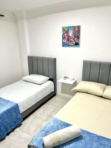 a bedroom with two beds and a painting on the wall at Apartamento Cerca al Complejo Deportivo in Valledupar