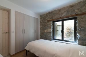 ein Schlafzimmer mit einer Steinmauer, einem Bett und einem Fenster in der Unterkunft Balkoni Moutoullas in Moutoullas