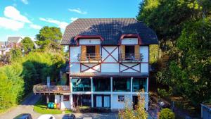 uma grande casa branca com um telhado preto em Pousada Apple House - Campos do Jordao em Campos do Jordão