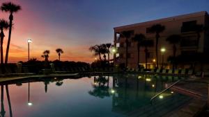 a swimming pool in front of a building with a sunset at Land's End 9-204 Beach Front in St Pete Beach