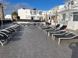 - une rangée de chaises longues et de parasols sur la terrasse dans l'établissement Los Gracioseras 2 Bed Apt no 218 - AC, WIFI, UK TV, à Tías