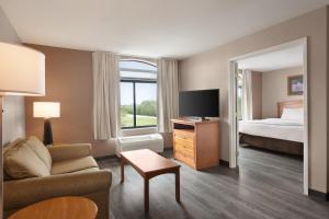 a hotel room with a couch and a bed at Wingate by Wyndham Bentonville in Bentonville