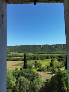 uma vista a partir de uma janela de um campo e árvores em Maison avec vue sur la vallée d'Asse em Saint-Julien-dʼAsse