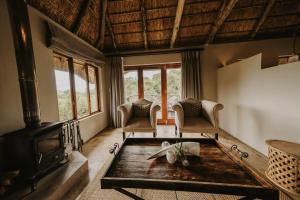 a living room with a fireplace and a table at Bukela Game Lodge - Amakhala Game Reserve in Amakhala Game Reserve