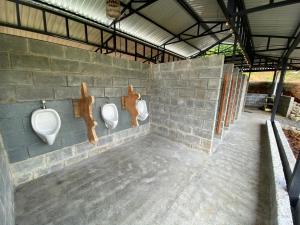 a bathroom with three urinals on a brick wall at Esquipulas Rainforest in Quepos
