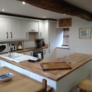 a kitchen with white cabinets and a wooden counter top at Wern Ddu, Defynnog - Brecon Beacons in Brecon