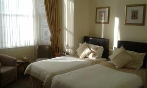 a hotel room with two beds and a window at Cedar Lodge in Llandudno