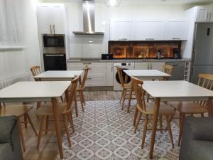 una cocina con mesas y sillas blancas. en CASA RURAL LA MANFORTA, en Gata