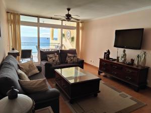 sala de estar con sofá y TV en By the Beach & Pool Apartment, en Funchal