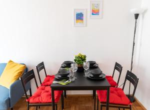 a dining room table with red cushions and a black table and chairs at Pal's Favoriten Apartment in Vienna