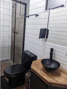 a bathroom with a black toilet and a sink at All Black Resort in Monte Verde
